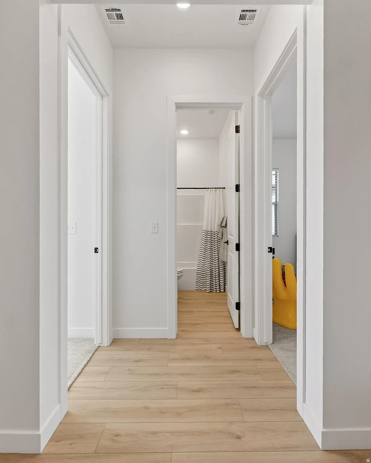 Hallway with light wood-style flooring and recessed lighting