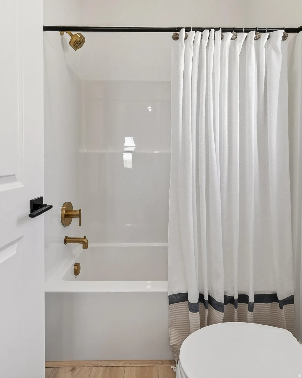 Bathroom with shower / tub combo and light wood-type flooring
