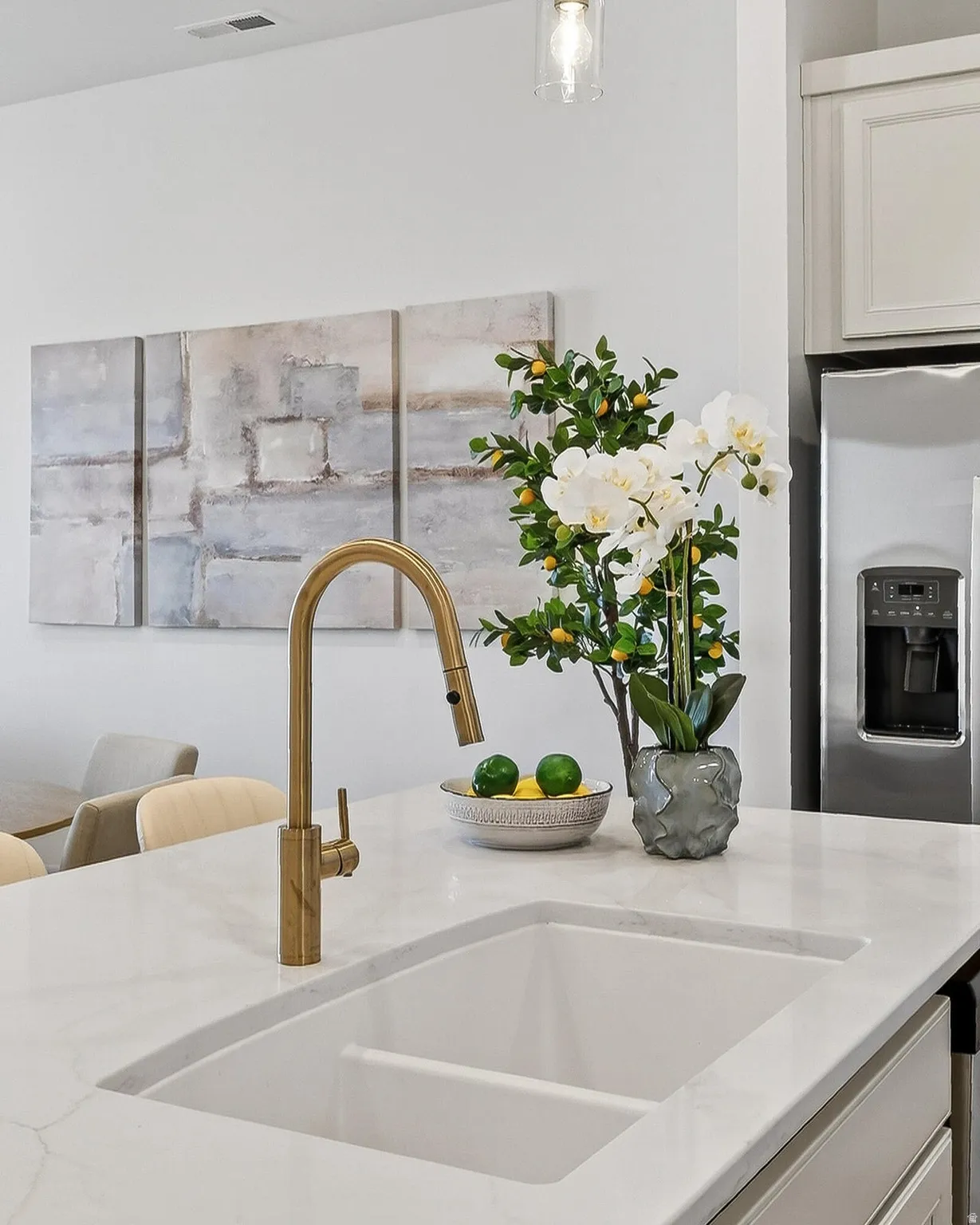 Kitchen view of stainless steel fridge with ice dispenser, light stone countertops, and white cabinetry