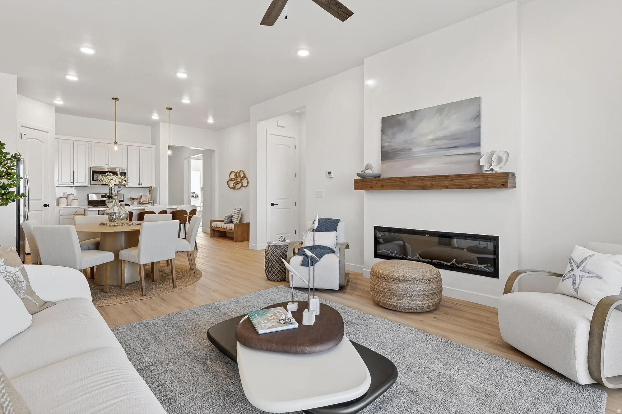 Living area with light wood-style flooring, a glass covered fireplace, ceiling fan, and recessed lighting