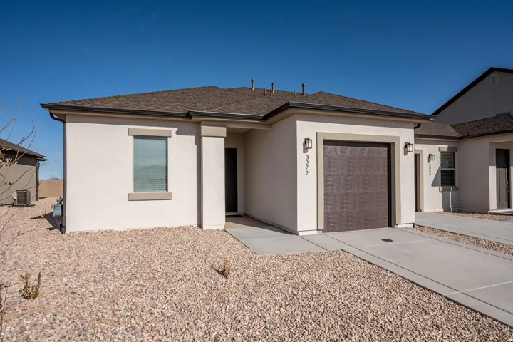 View of front facade with a garage, stucco siding, driveway, and roof with shingles