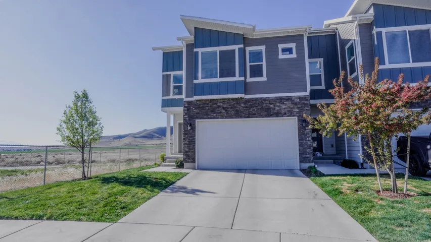 View of front facade with stone siding, board and batten siding, a garage, concrete driveway, and a mountain view