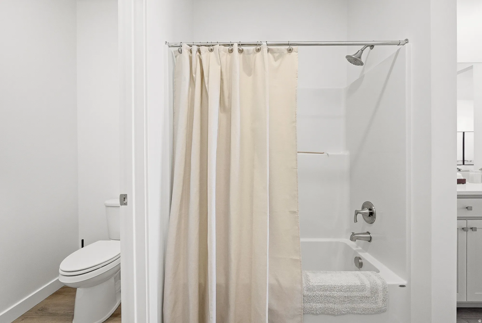 Bathroom featuring vanity, shower / bath combo, and wood finished floors
