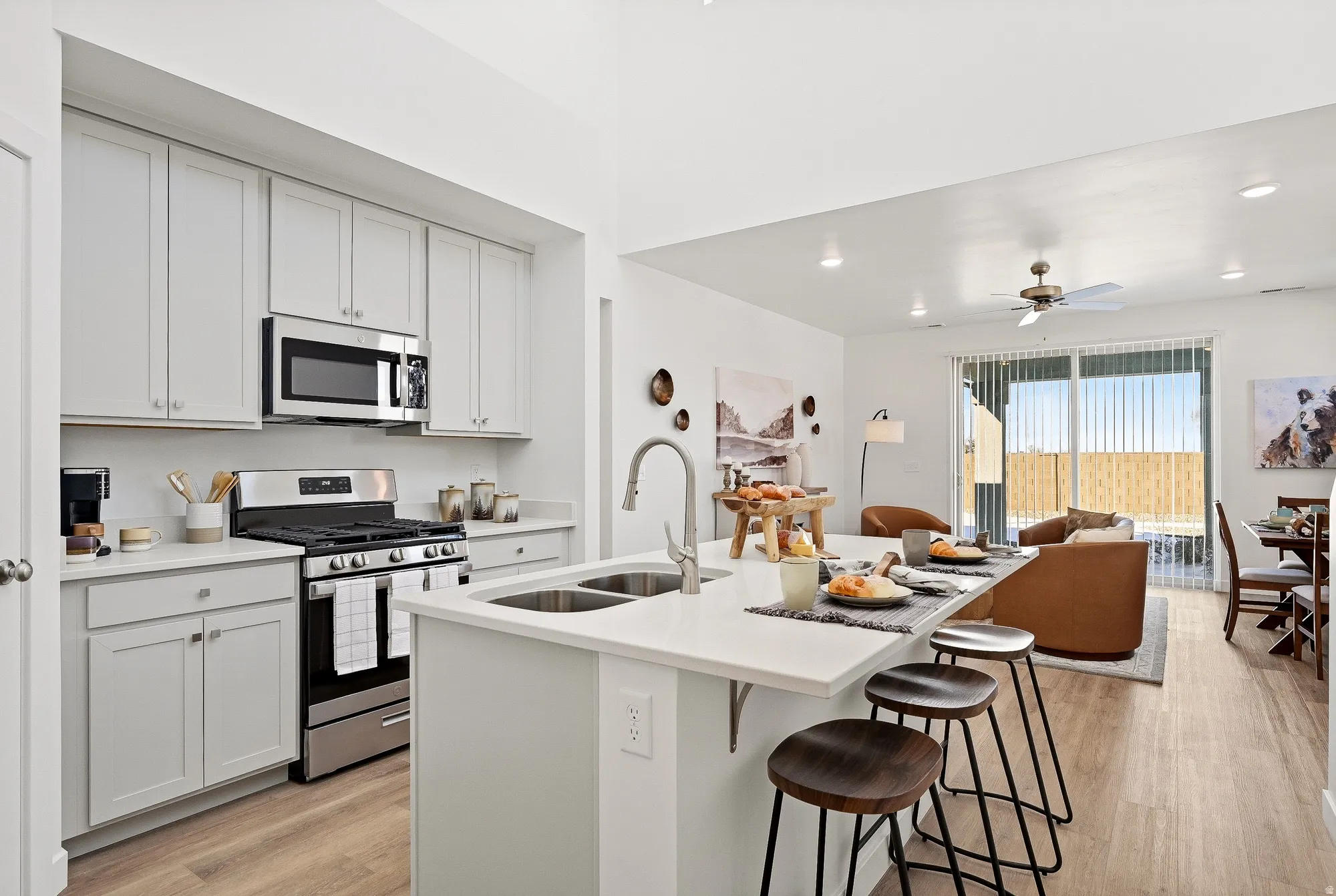 Kitchen with stainless steel appliances, a breakfast bar, light wood-style flooring, an island with sink, and open floor plan