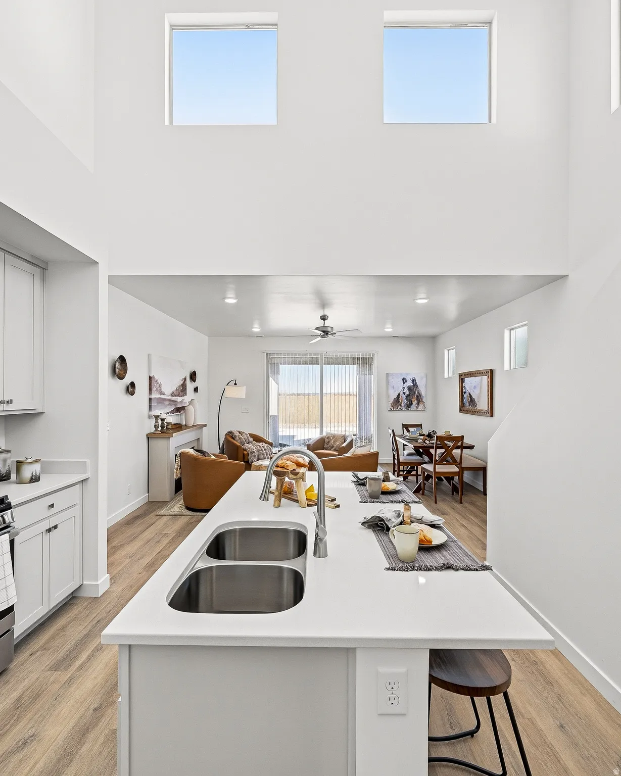 Kitchen featuring open floor plan, an island with sink, light wood-style flooring, white cabinets, and a high ceiling