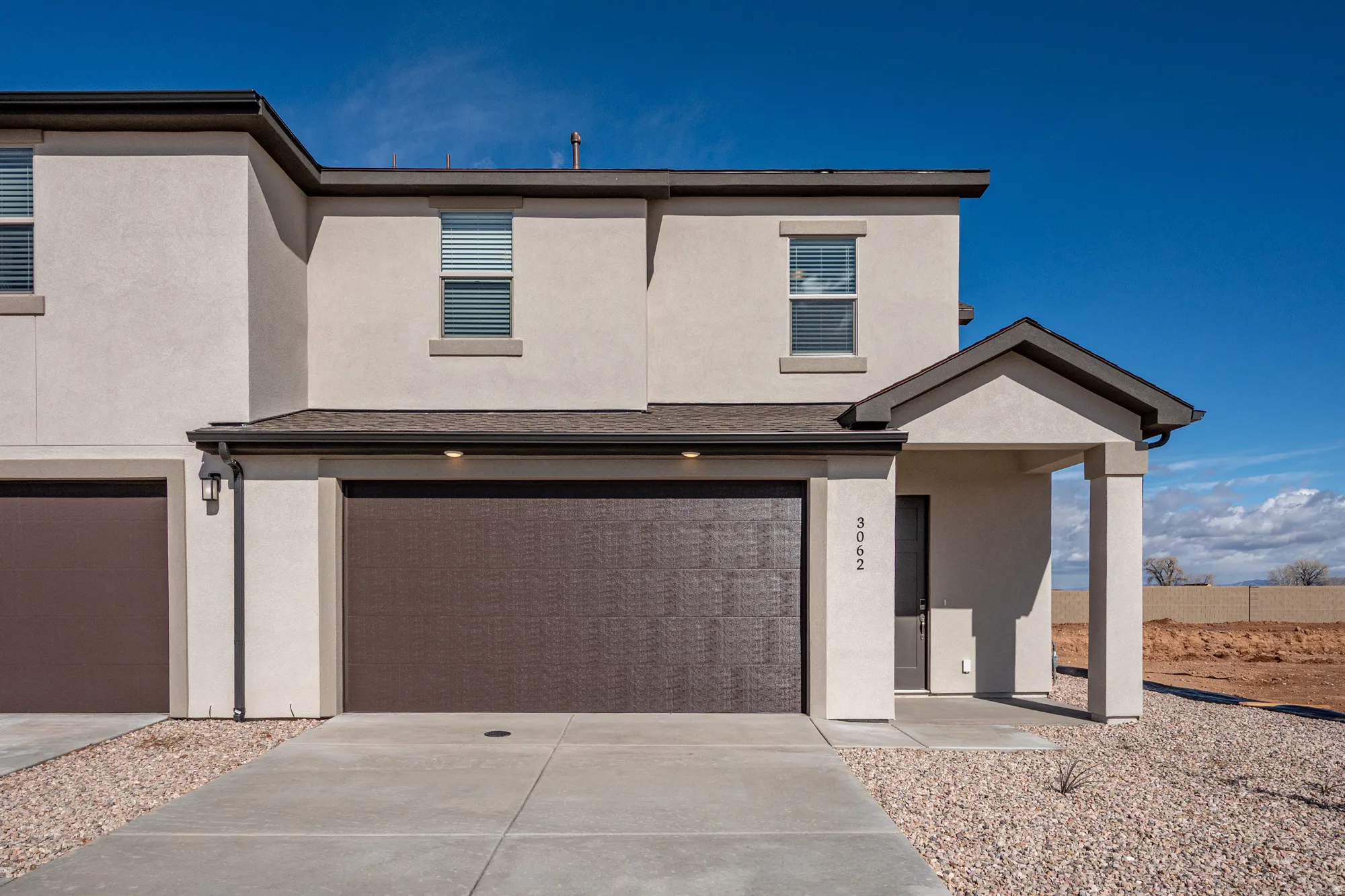 View of front of home featuring stucco siding, a garage, and driveway