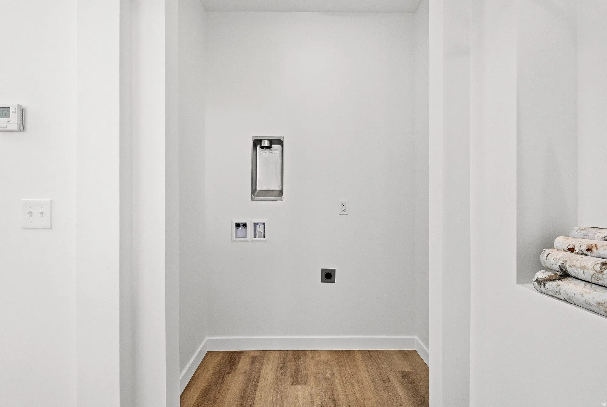 Laundry area with hookup for an electric dryer, light wood-style flooring, and hookup for a washing machine