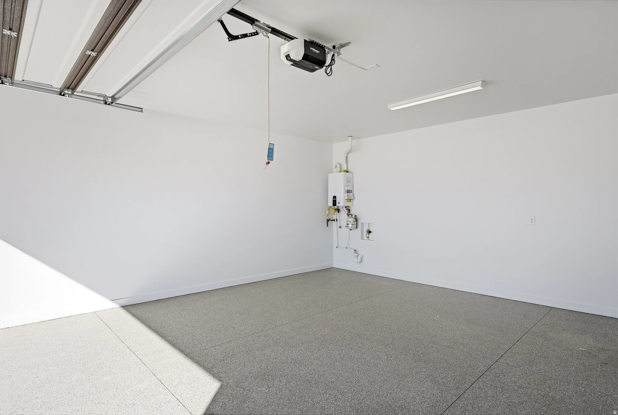 Garage featuring tankless water heater and a garage door opener