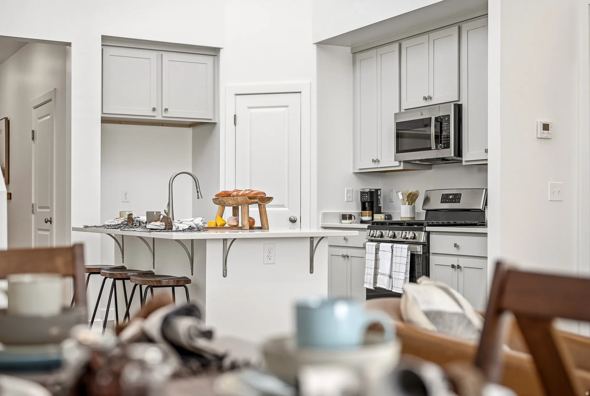 Kitchen featuring a breakfast bar area, an island with sink, stainless steel appliances, and white cabinetry