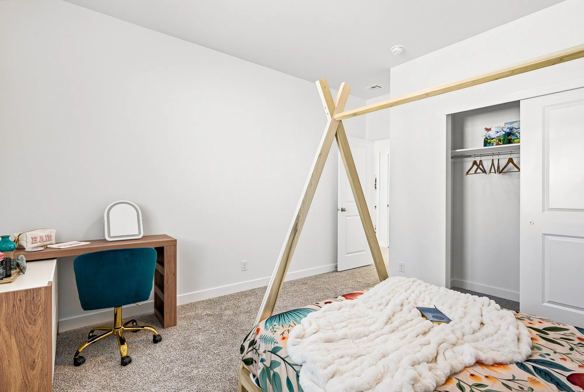 Bedroom featuring light colored carpet, a desk, and a closet