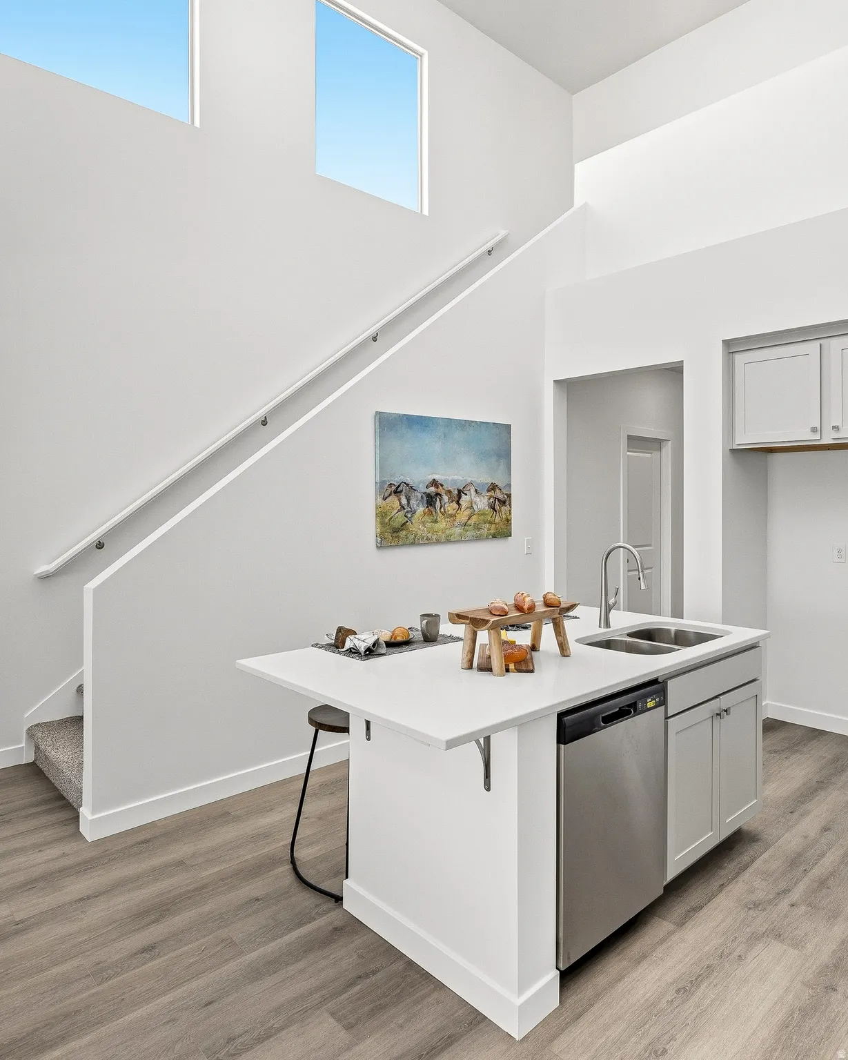 Kitchen with a kitchen breakfast bar, light wood-type flooring, dishwasher, a kitchen island with sink, and a high ceiling