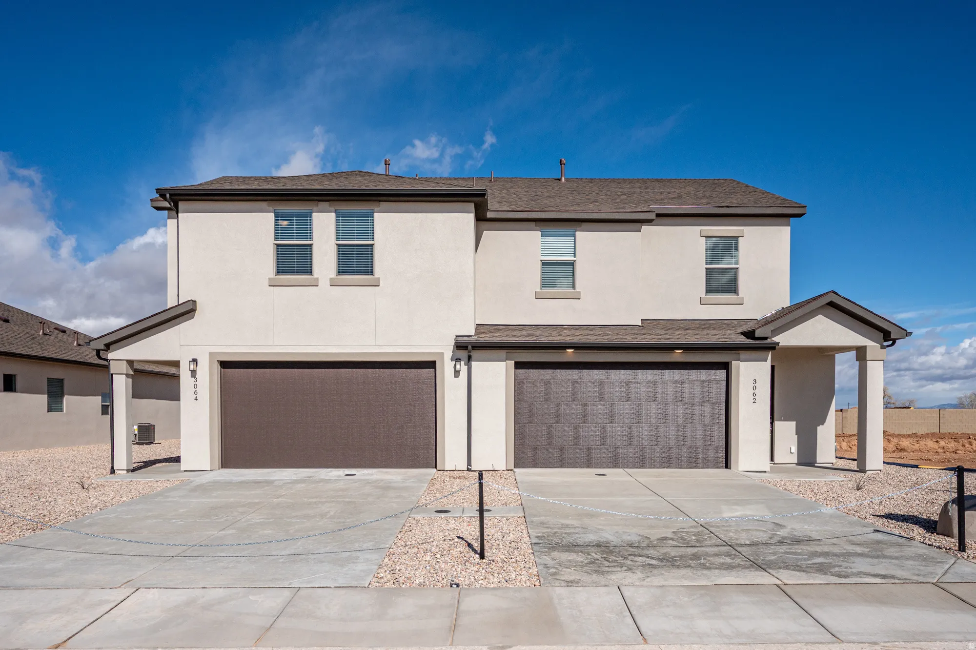 Traditional-style house with an attached garage, stucco siding, driveway, and a shingled roof