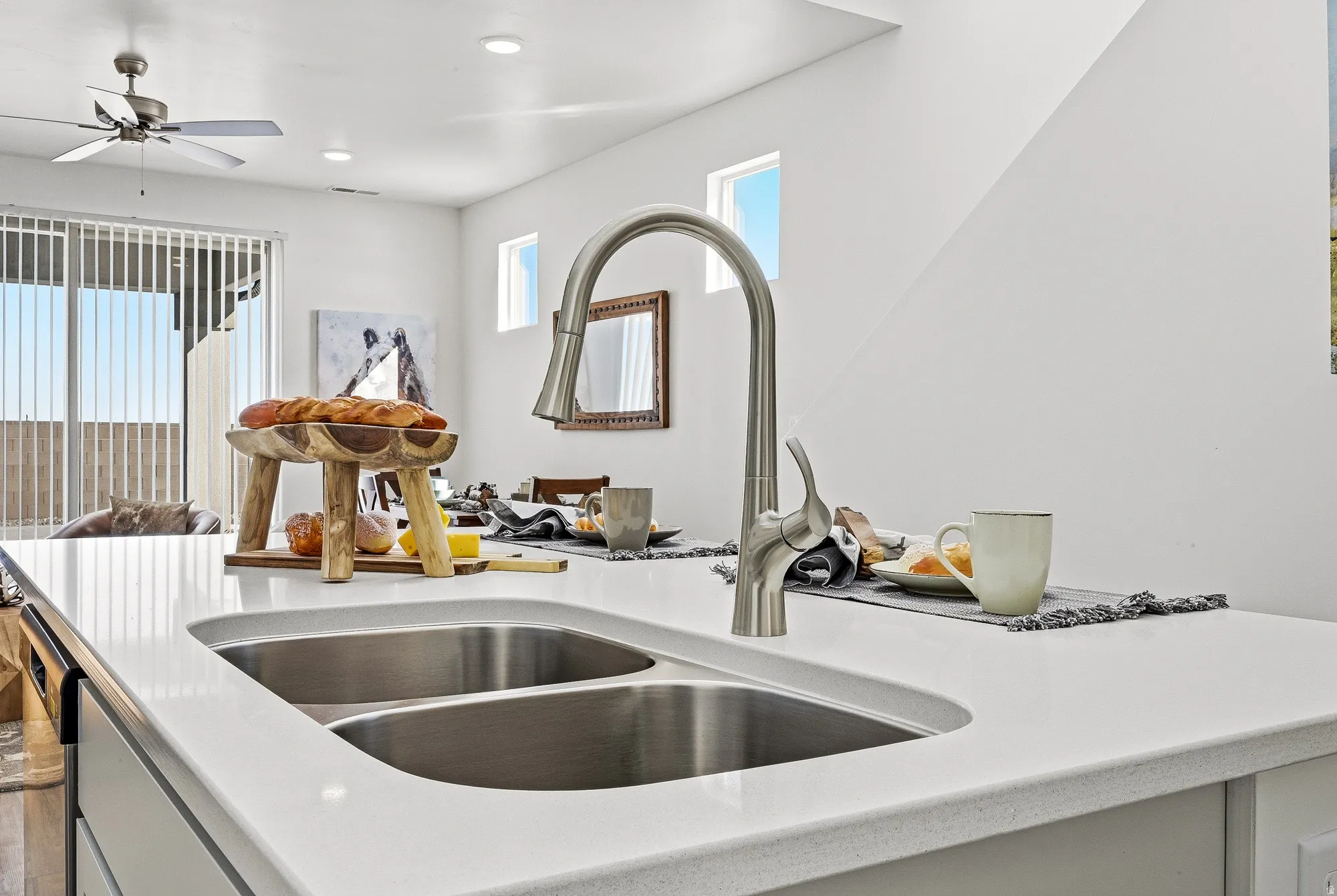 Kitchen view of a ceiling fan, light stone countertops, and stainless steel dishwasher