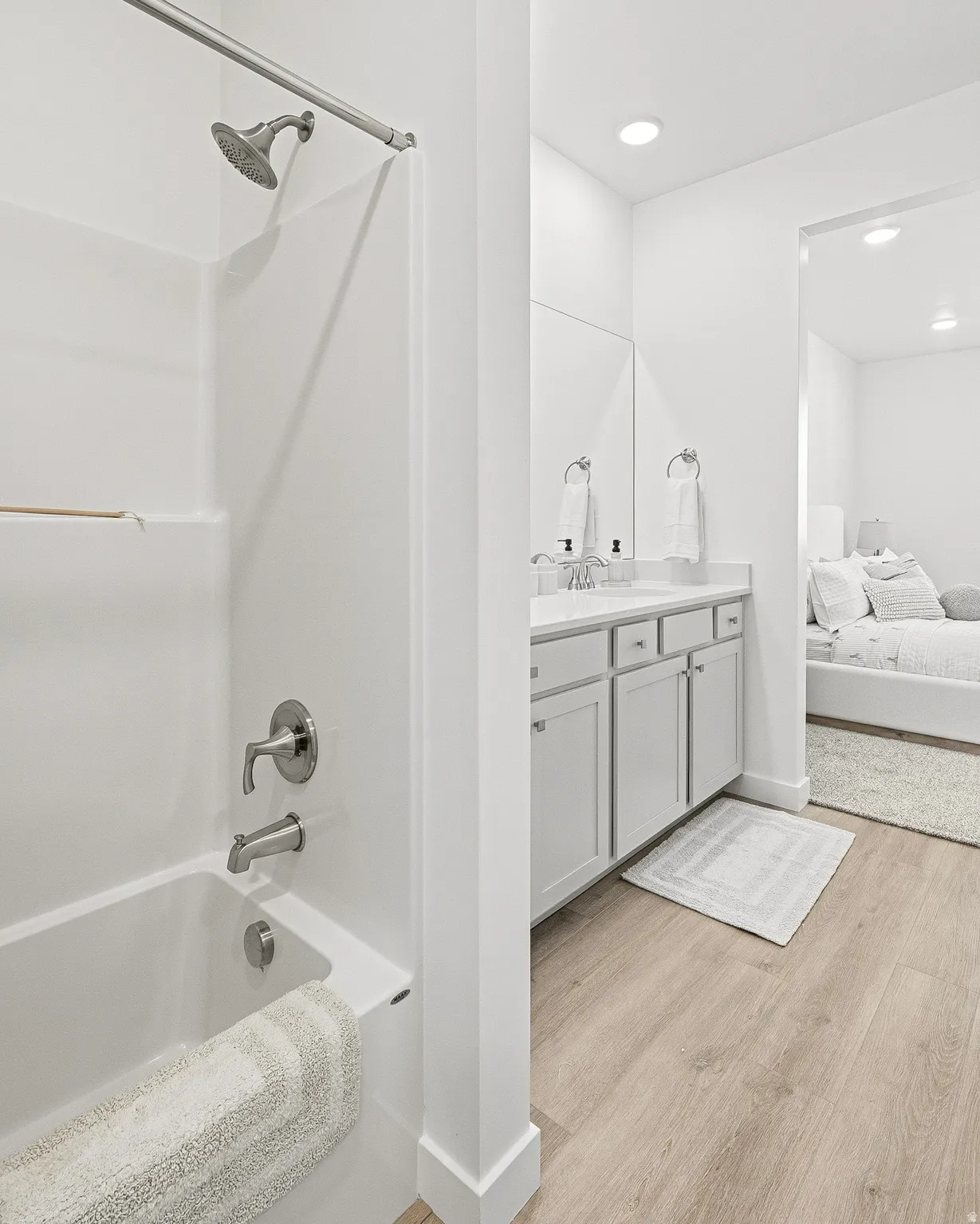 Ensuite bathroom featuring vanity, light wood-type flooring, washtub / shower combination, and recessed lighting