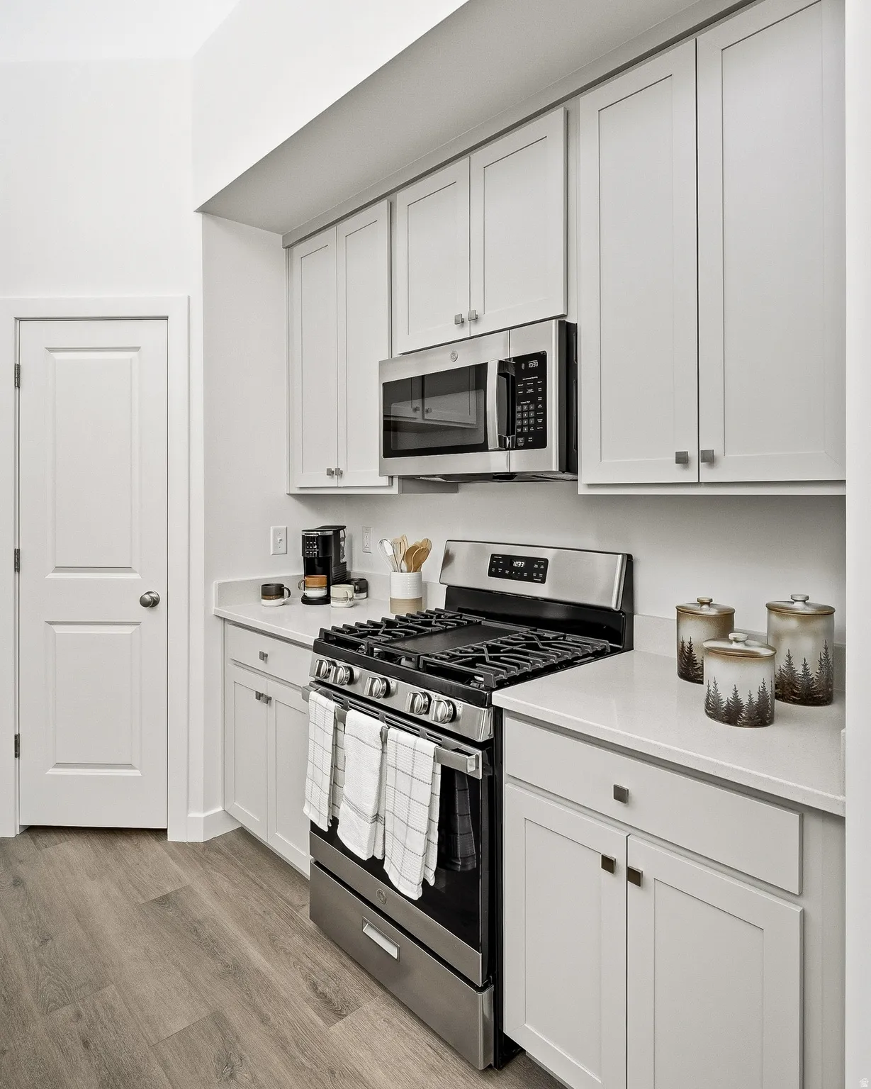 Kitchen featuring stainless steel appliances, white cabinets, and light wood-style flooring