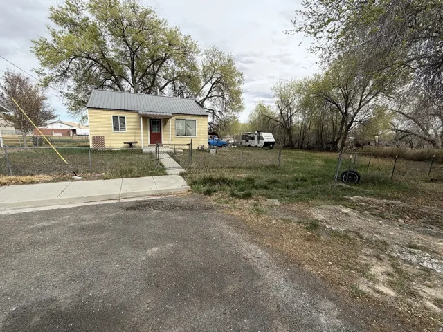 Bungalow-style home with a fenced front yard and a metal roof