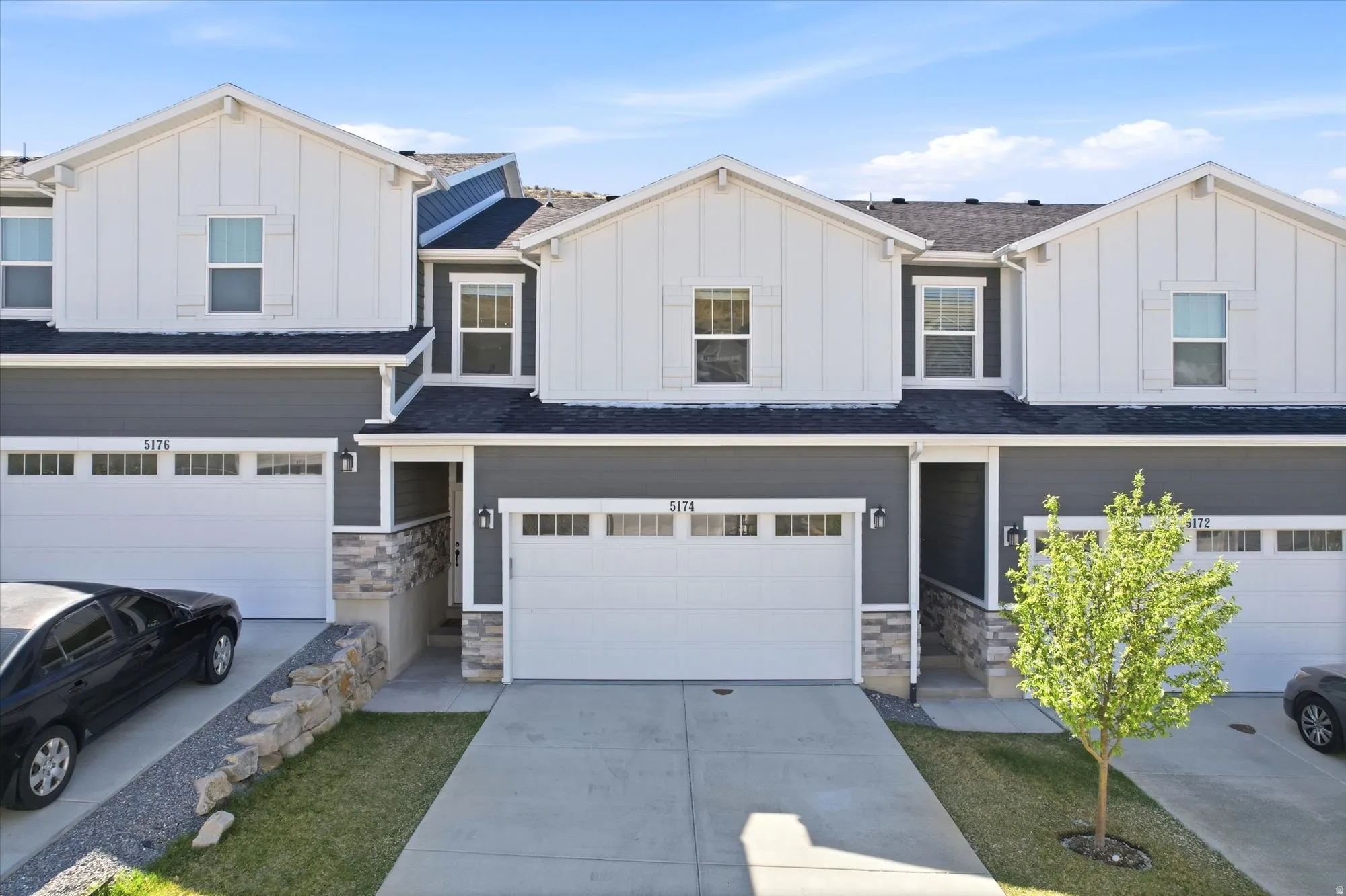 View of front of property with board and batten siding, stone siding, a garage, and driveway