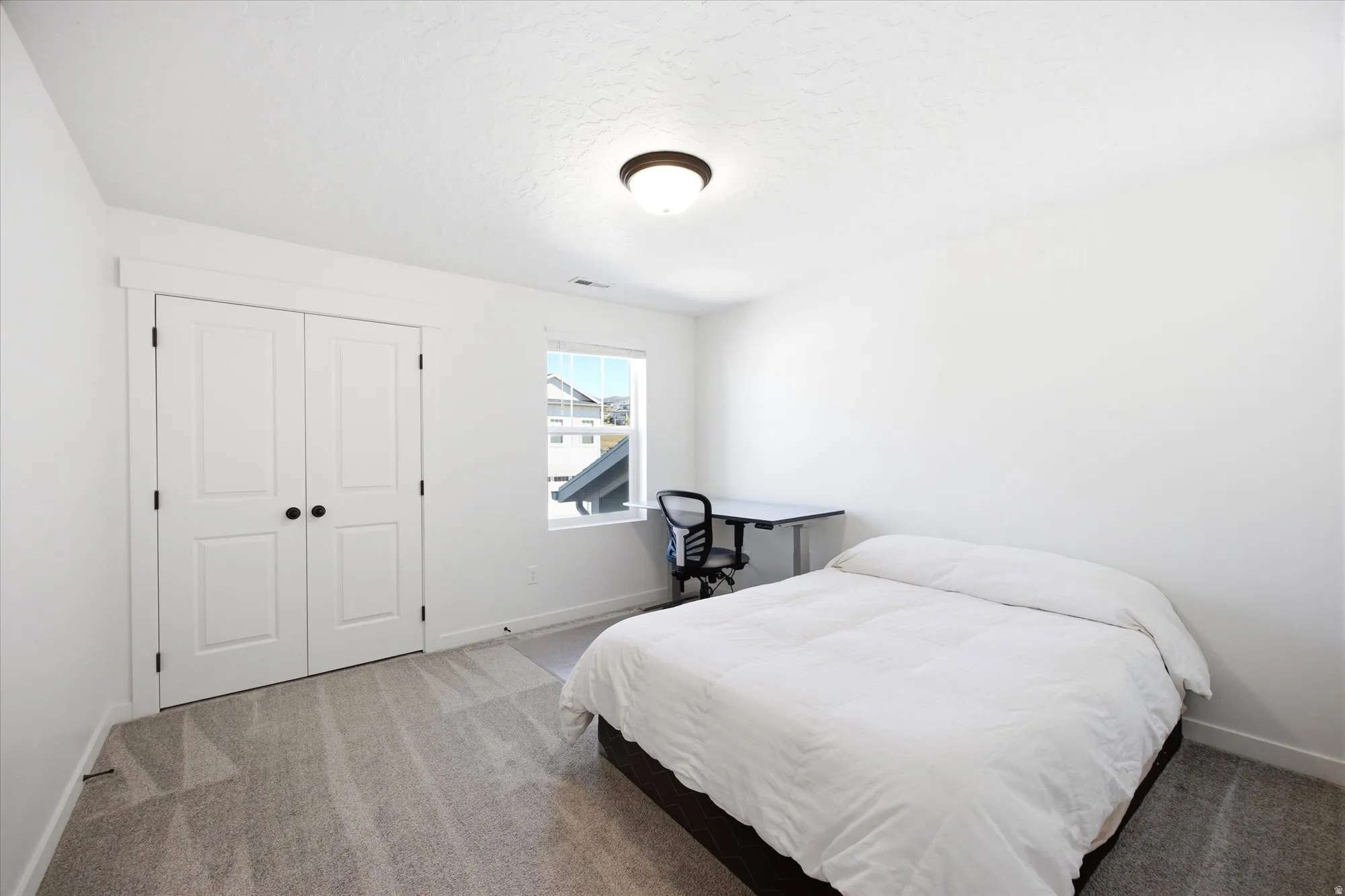 Bedroom with light colored carpet, a closet, and a textured ceiling
