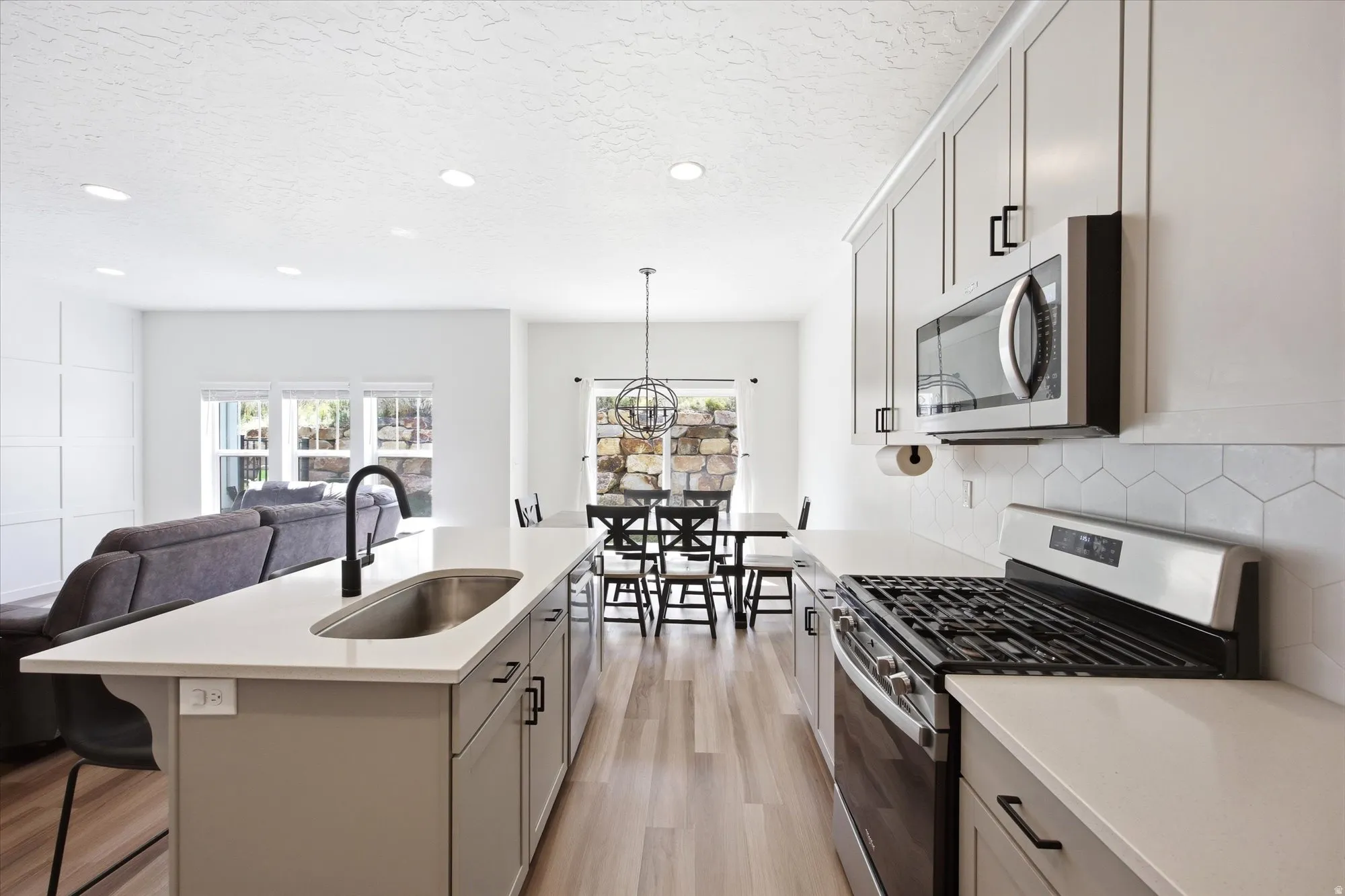 Kitchen featuring stainless steel appliances, open floor plan, light wood finished floors, a breakfast bar area, and an island with sink
