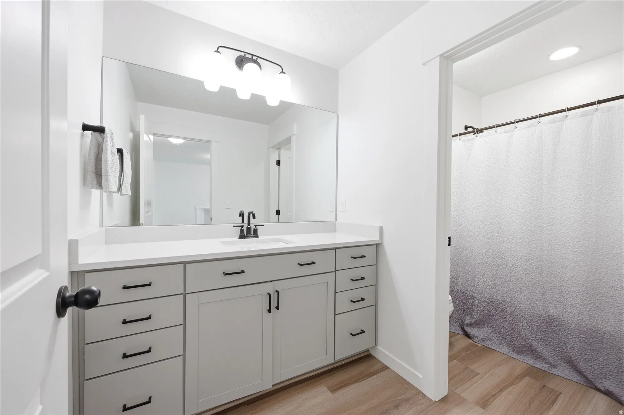 Full bathroom with vanity, a shower with curtain, and light wood-style floors