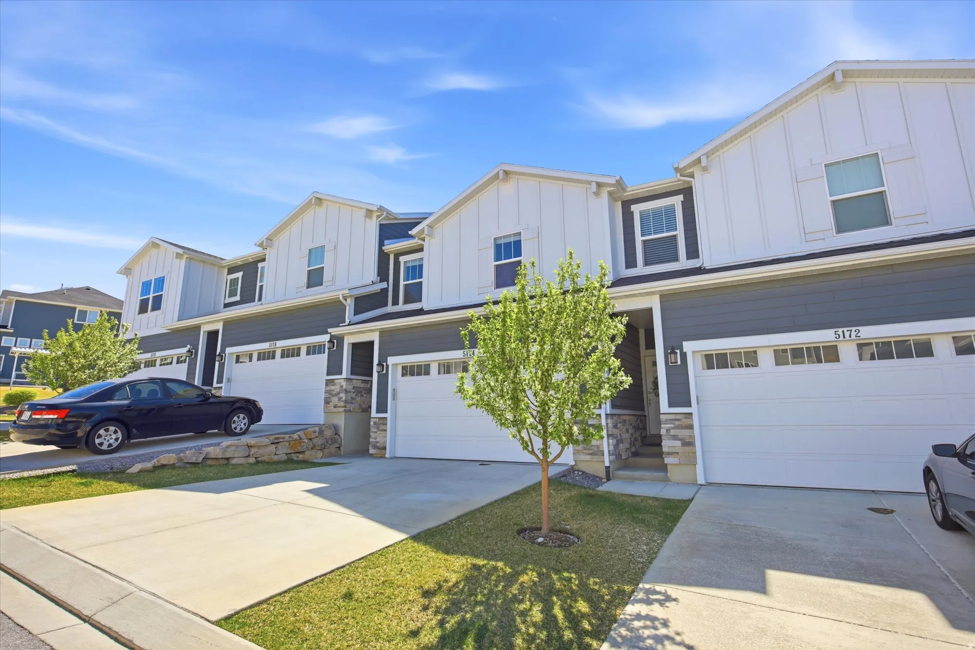 Craftsman-style home featuring an attached garage, board and batten siding, stone siding, and concrete driveway