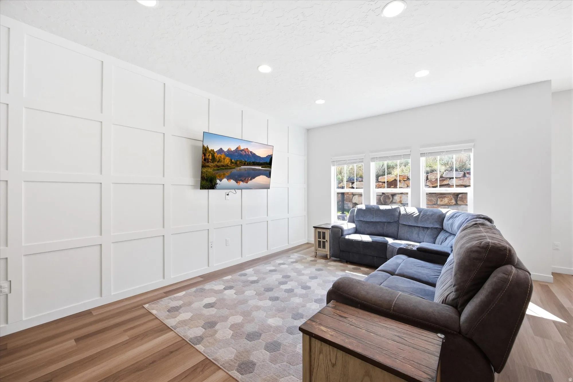 Living area featuring a decorative wall, light wood-style floors, recessed lighting, and a textured ceiling