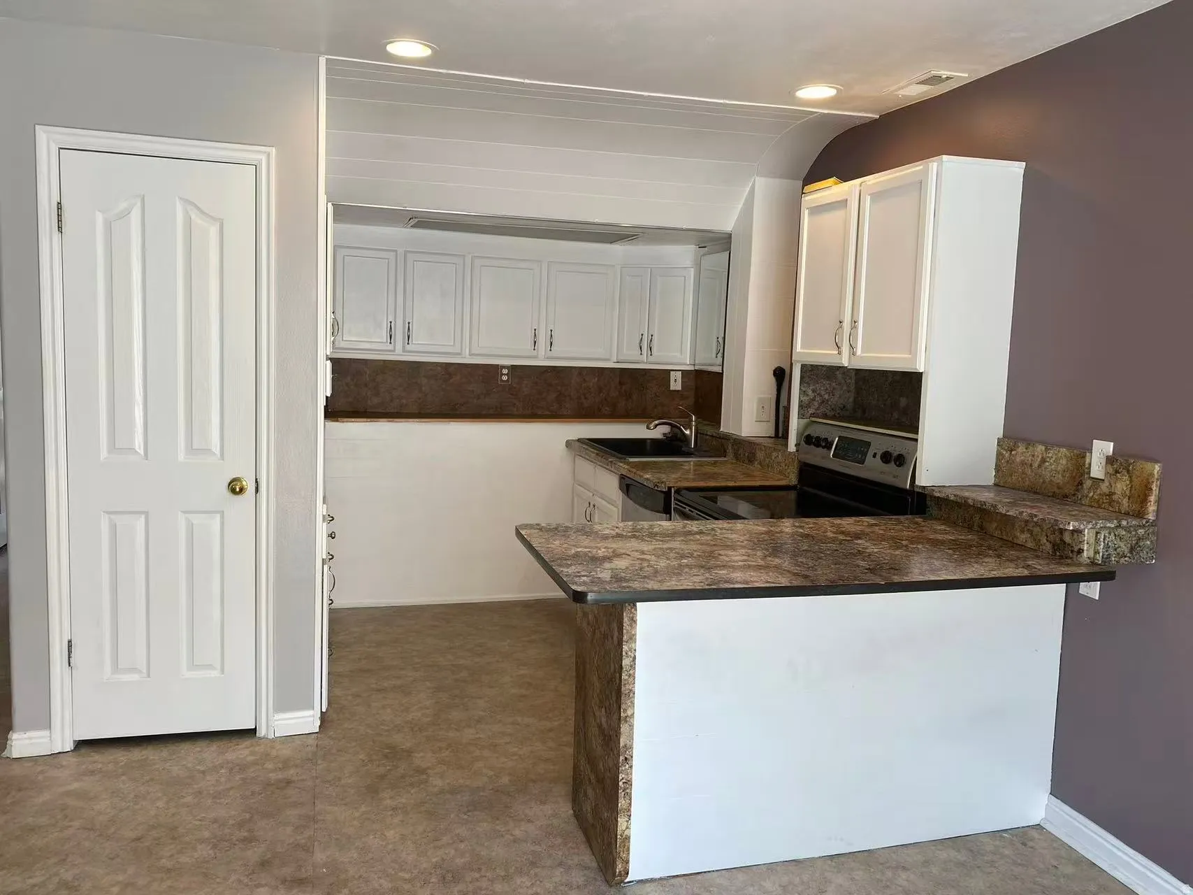Kitchen featuring a peninsula, white cabinets, stainless steel appliances, and a breakfast bar