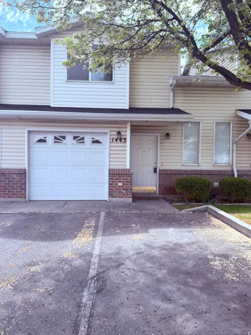 Traditional townhome featuring brick siding, a garage, and asphalt driveway