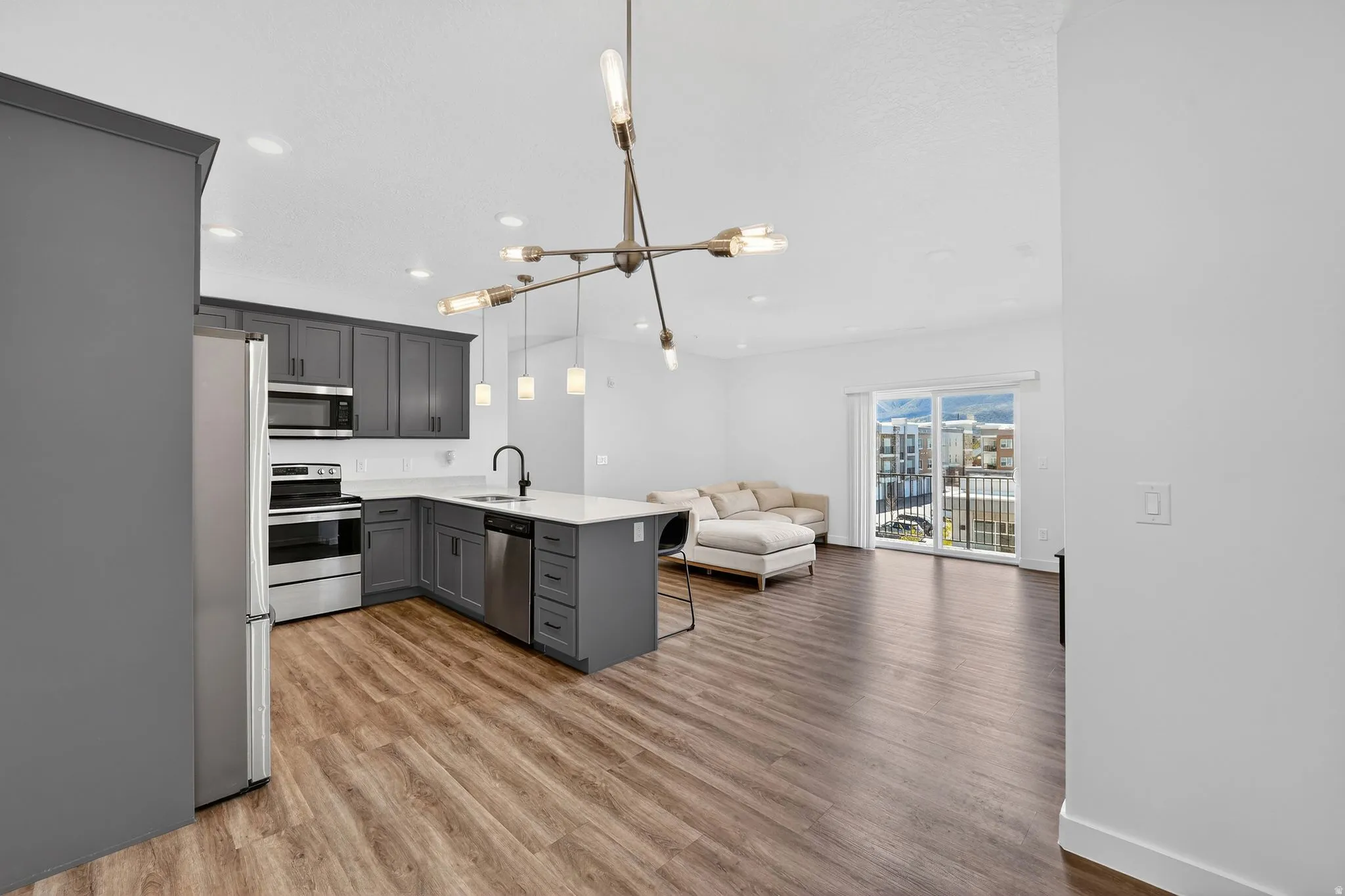 Kitchen with a peninsula, a breakfast bar area, open floor plan, stainless steel appliances, and light wood-type flooring