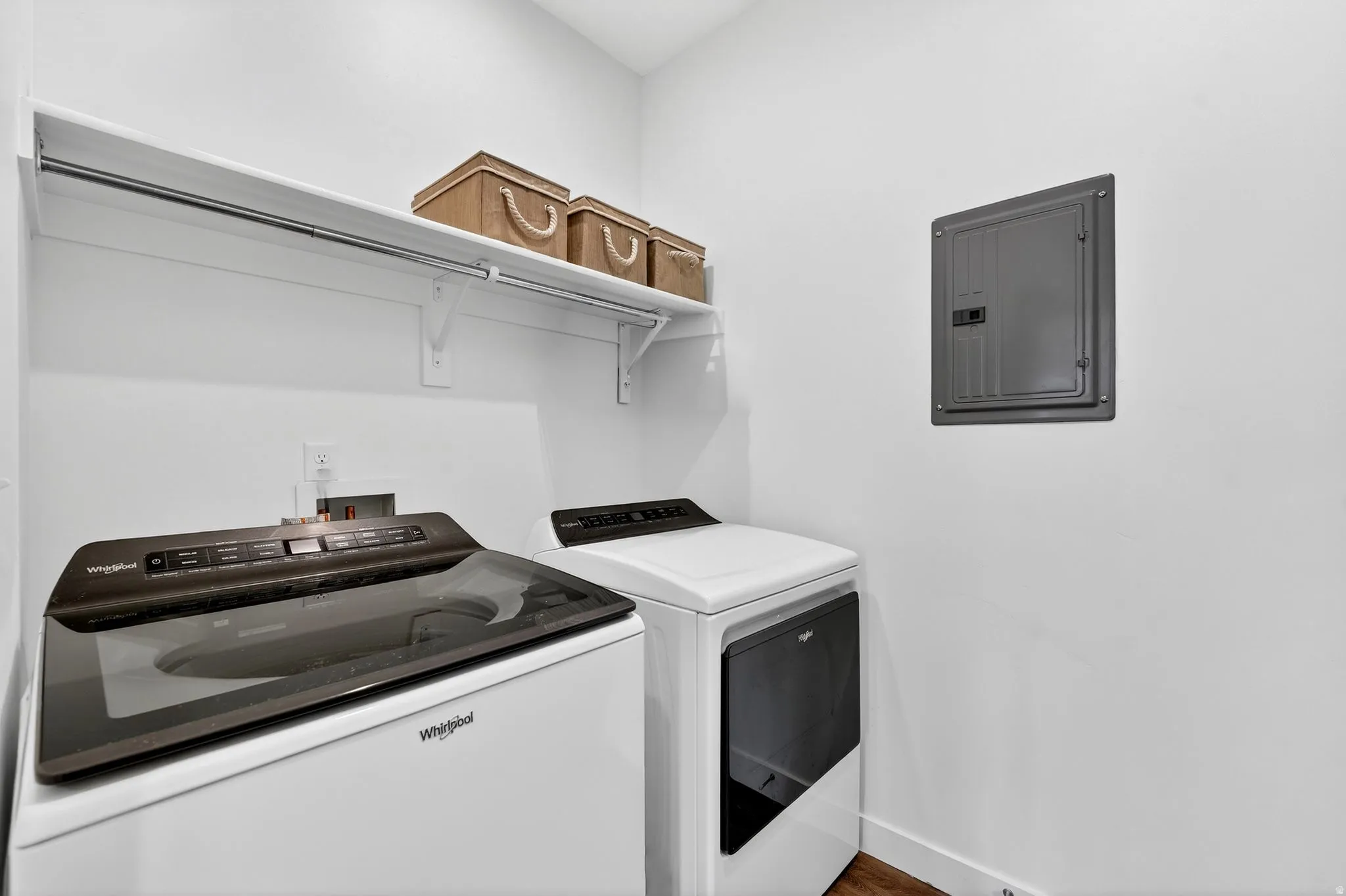 Laundry room featuring electric panel, washing machine and dryer, and wood finished floors