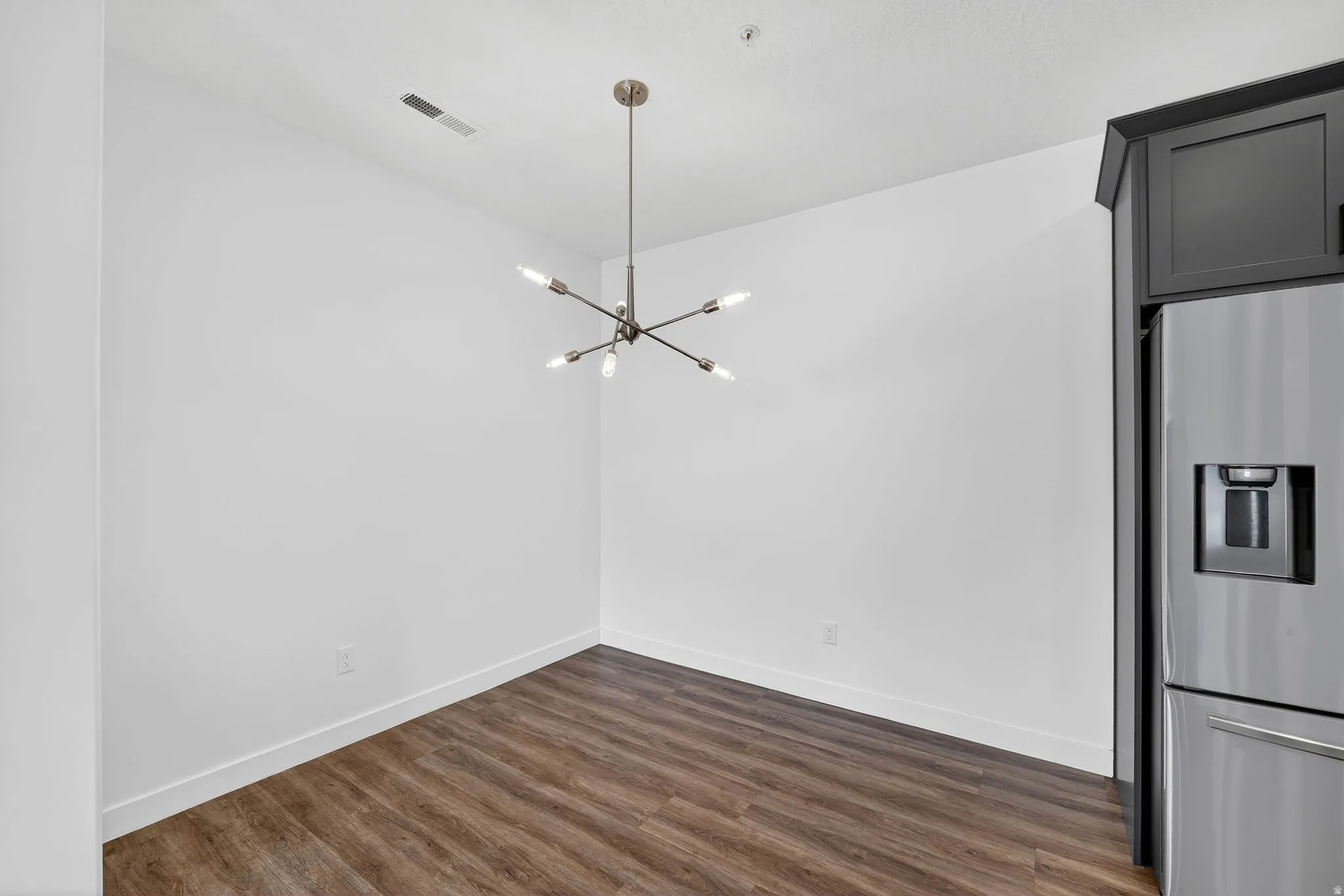 Unfurnished dining area with suspended lighting and dark wood-type flooring