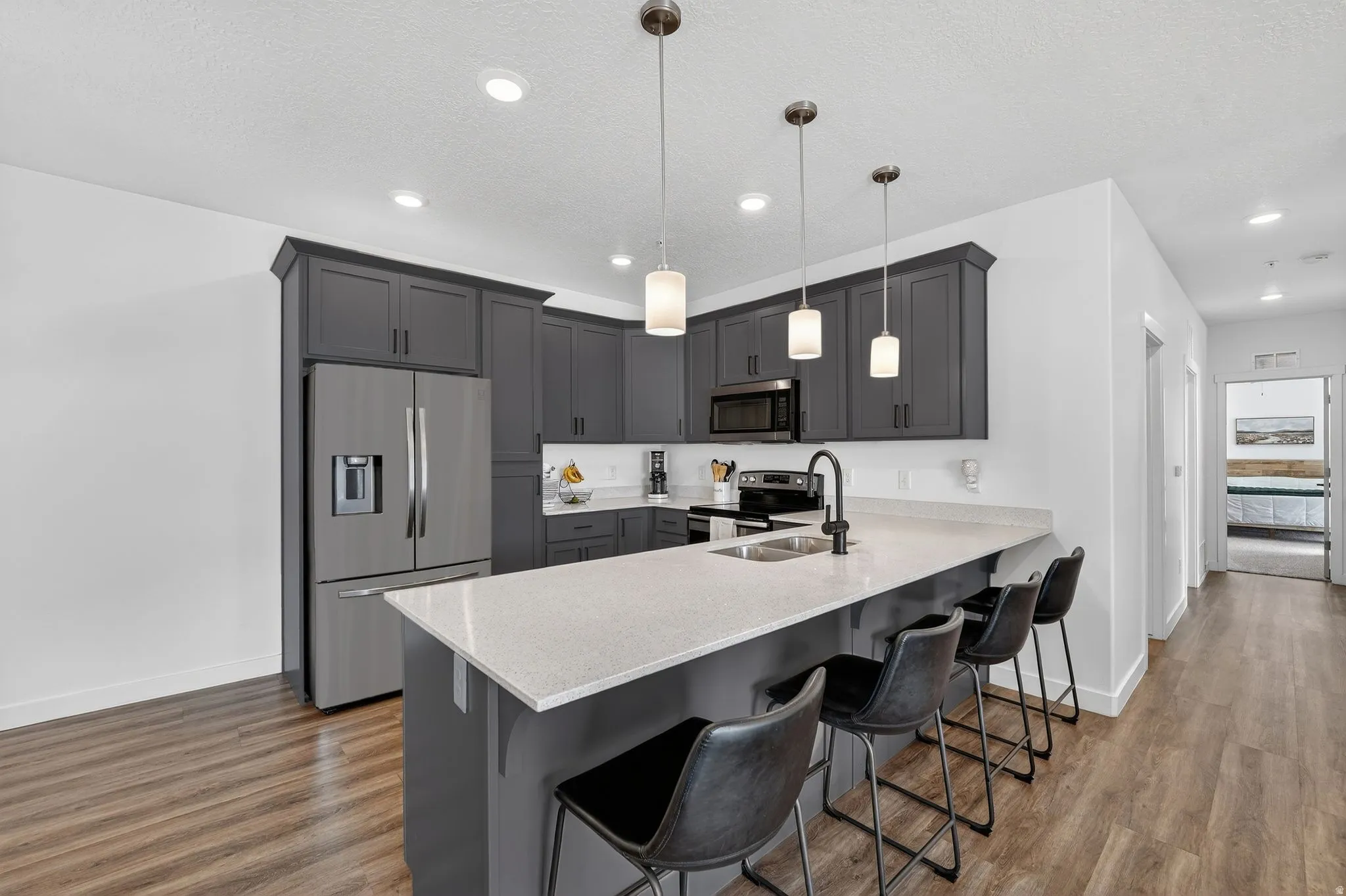 Kitchen with stainless steel appliances, a kitchen bar, a peninsula, decorative light fixtures, and gray cabinetry