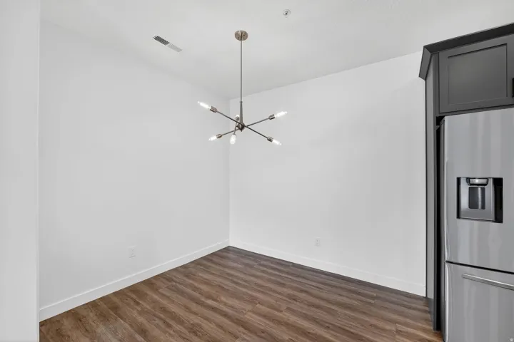 Unfurnished dining area with suspended lighting and dark wood-type flooring