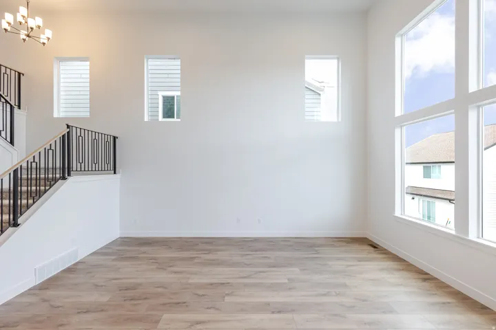 Expansive interior space featuring a double-height ceiling, large multi-pane windows, and light wood-finish flooring