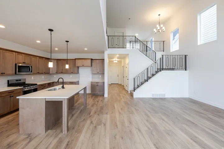 Open-concept living space featuring wood-finish flooring, a contemporary kitchen, and a two-story entryway