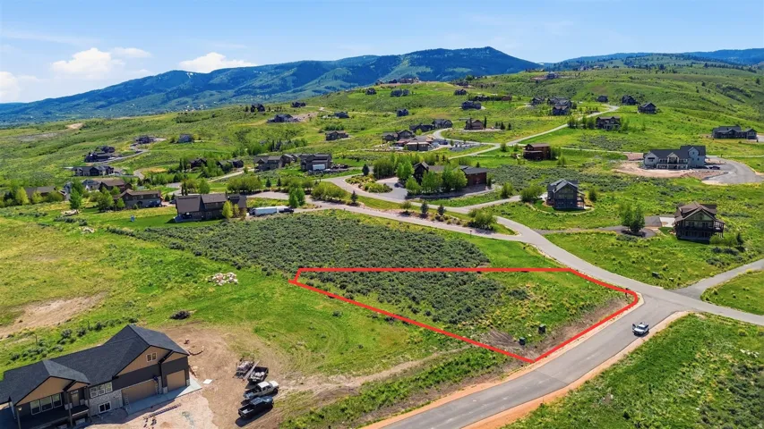 Expansive land lot featuring natural green vegetation, a paved road frontage, and surrounding residential properties