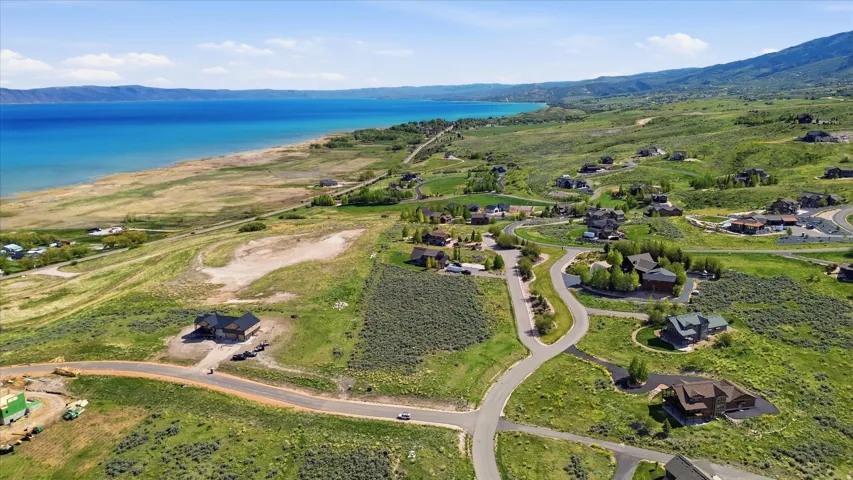 Expansive aerial landscape featuring a large body of water, distant mountains, and a winding paved road system