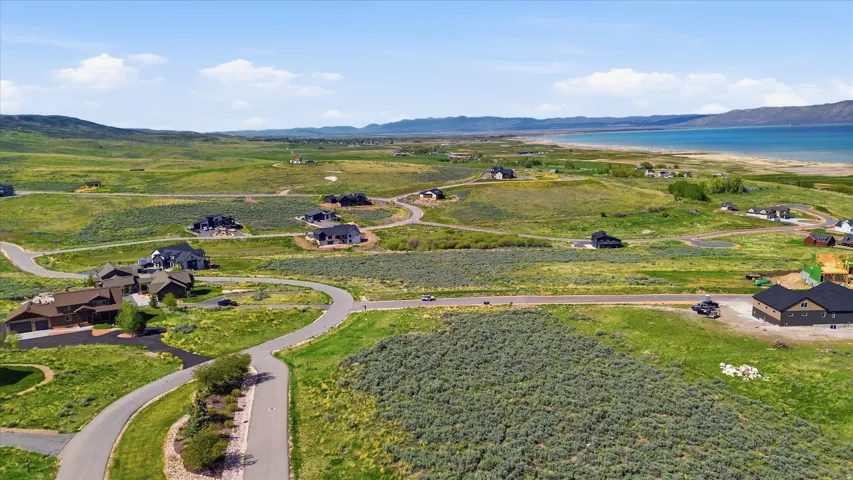 Expansive undeveloped lots within a residential community, featuring paved roads and distant lake frontage