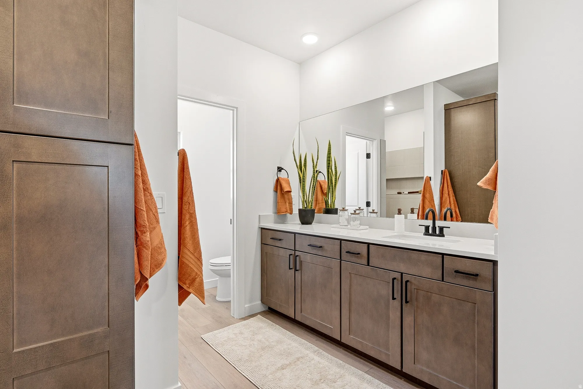 Full bath with double vanity and light wood-type flooring
