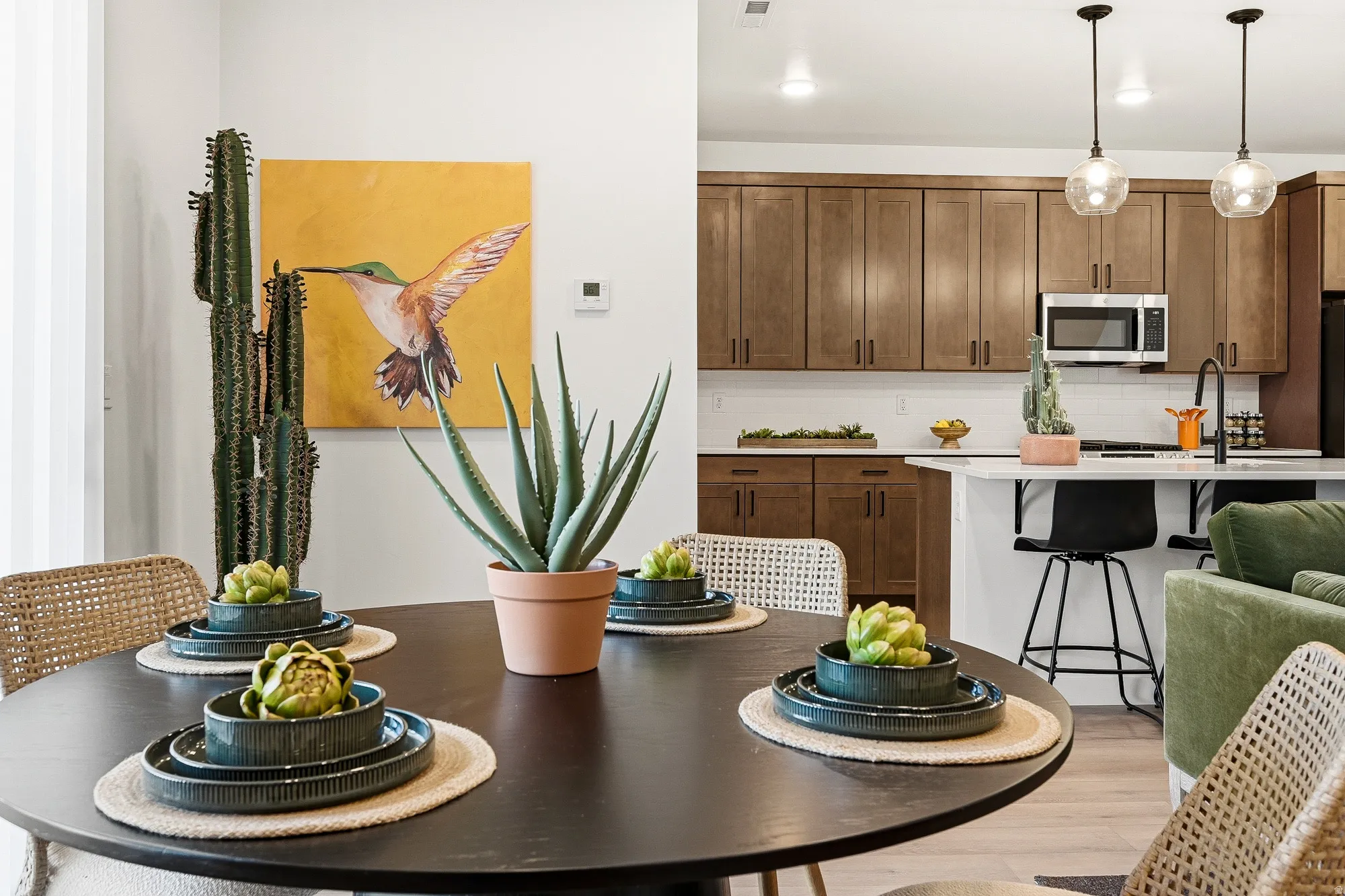 Kitchen featuring a kitchen breakfast bar, wood finish cabinetry, stainless steel microwave, hanging light fixtures, and tasteful backsplash
