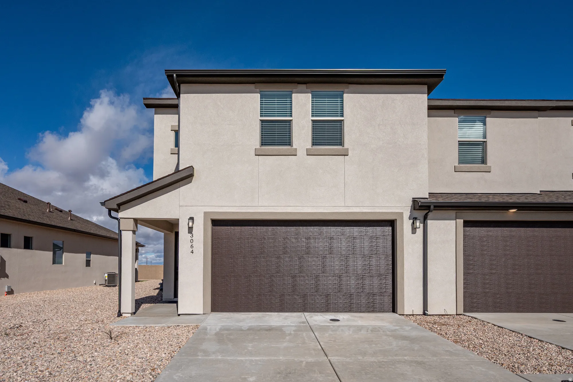 View of front of home with stucco siding, an attached garage, and concrete driveway