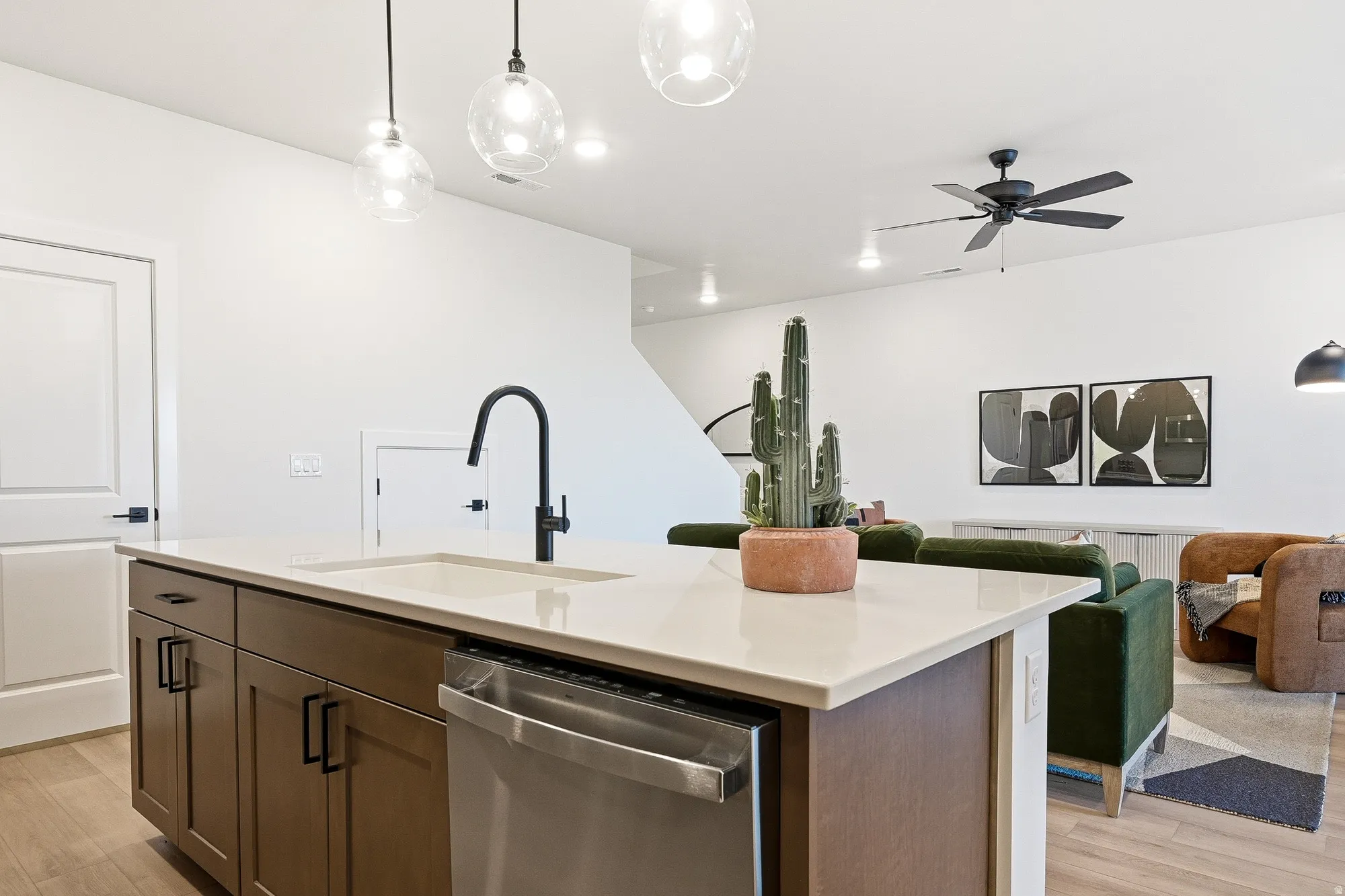 Kitchen featuring decorative light fixtures, dishwasher, light wood finished floors, and open floor plan