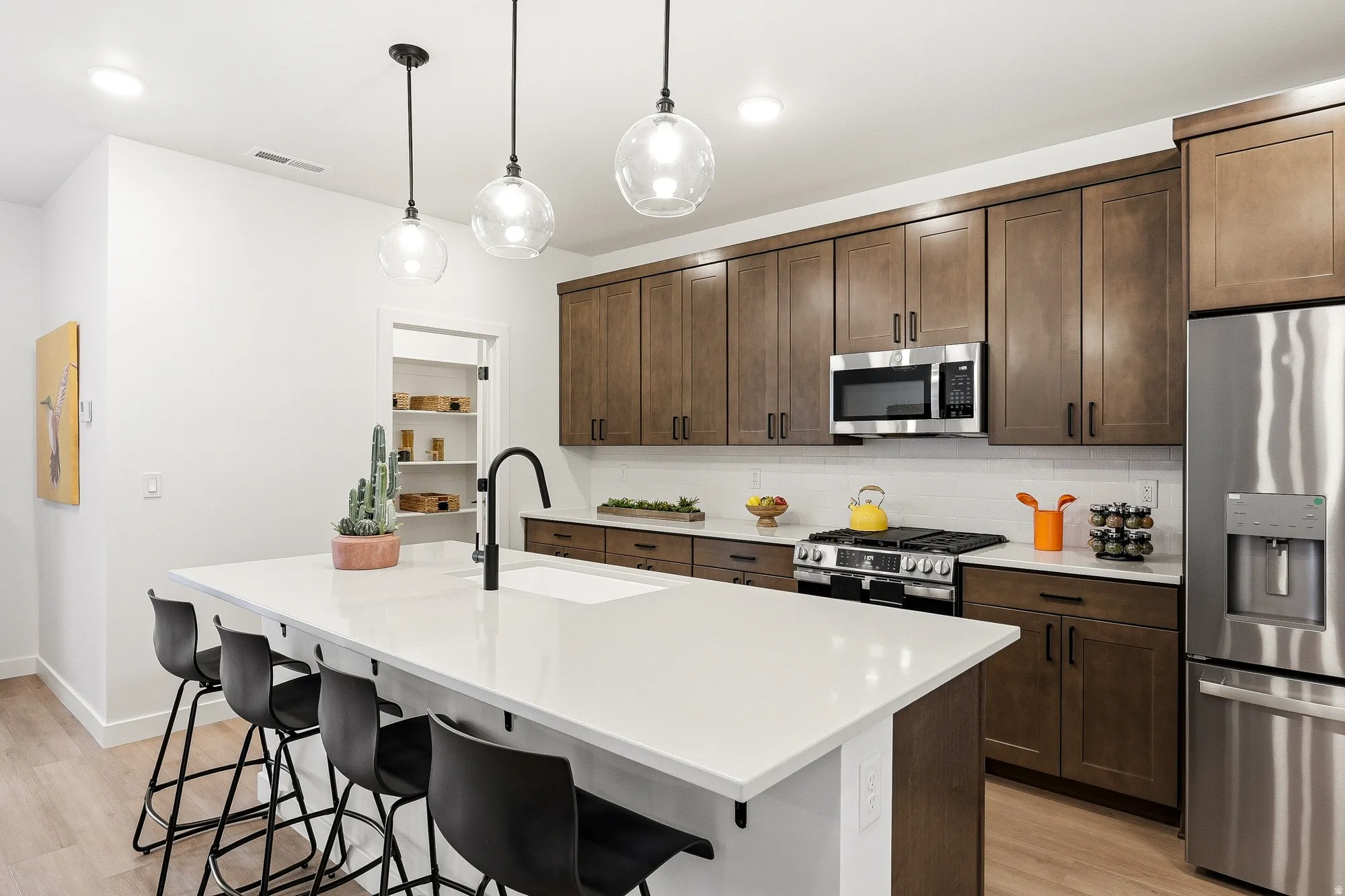 Kitchen with stainless steel appliances, a breakfast bar, backsplash, light wood finished floors, and dark wood finish cabinets