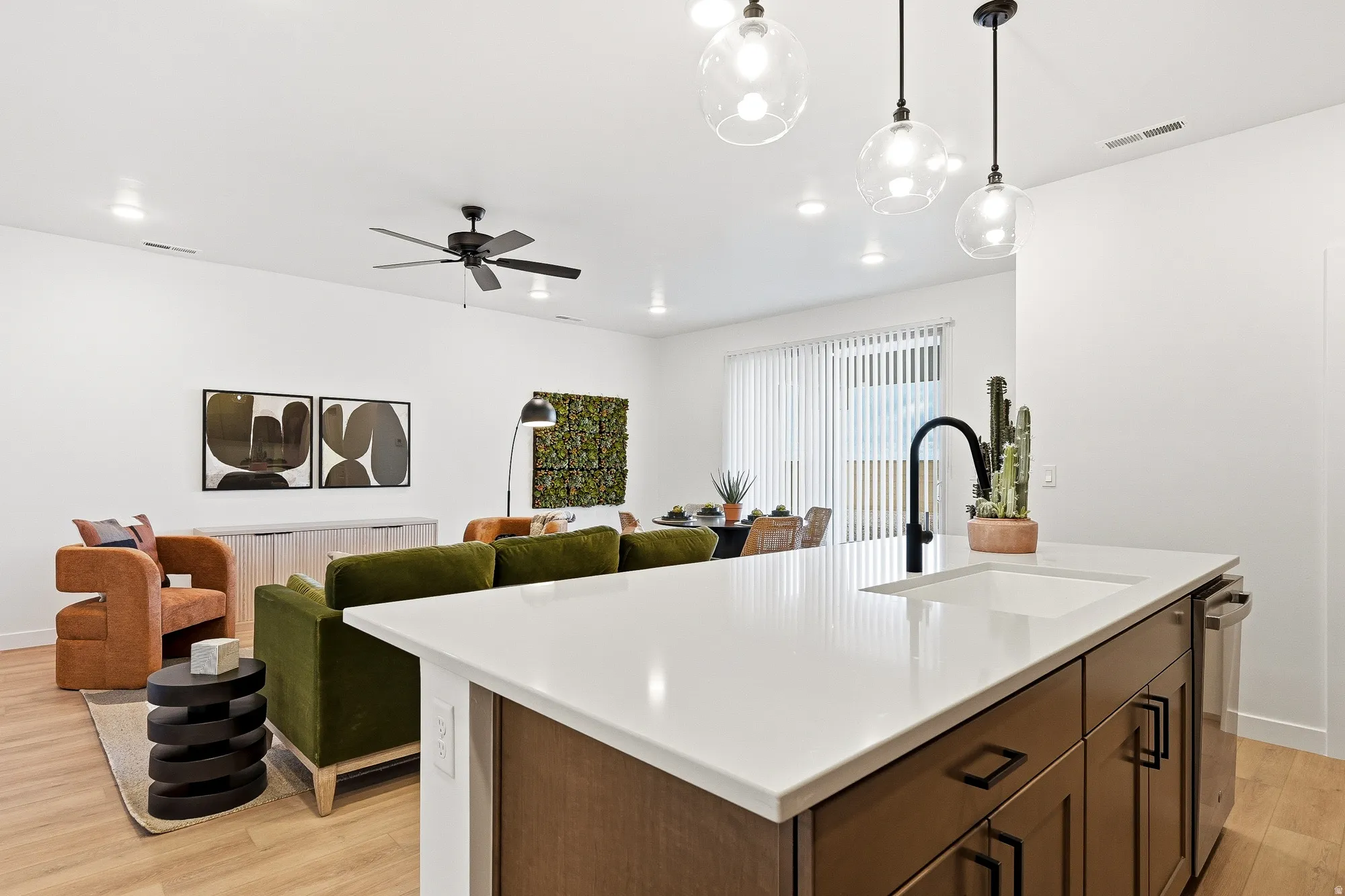 Kitchen featuring light wood-type flooring, a kitchen island with sink, decorative light fixtures, a ceiling fan, and open floor plan
