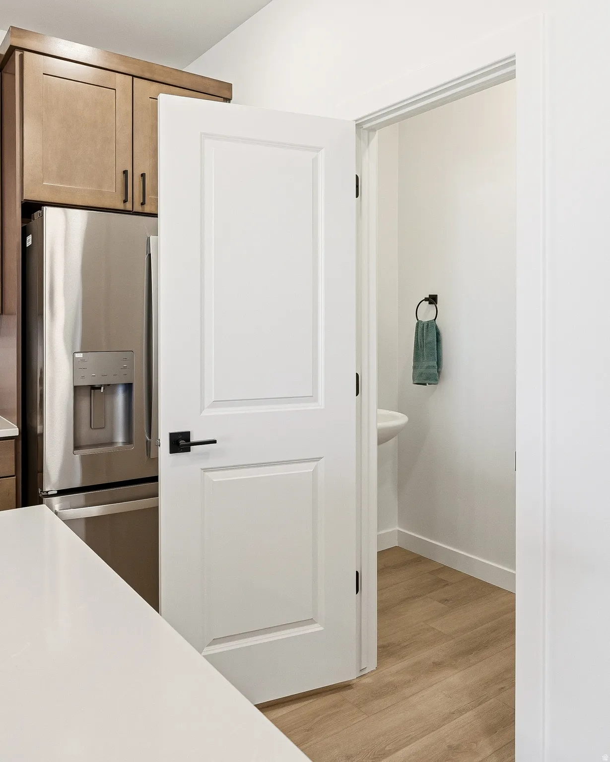 Kitchen with stainless steel fridge, light wood-style flooring, and light countertops