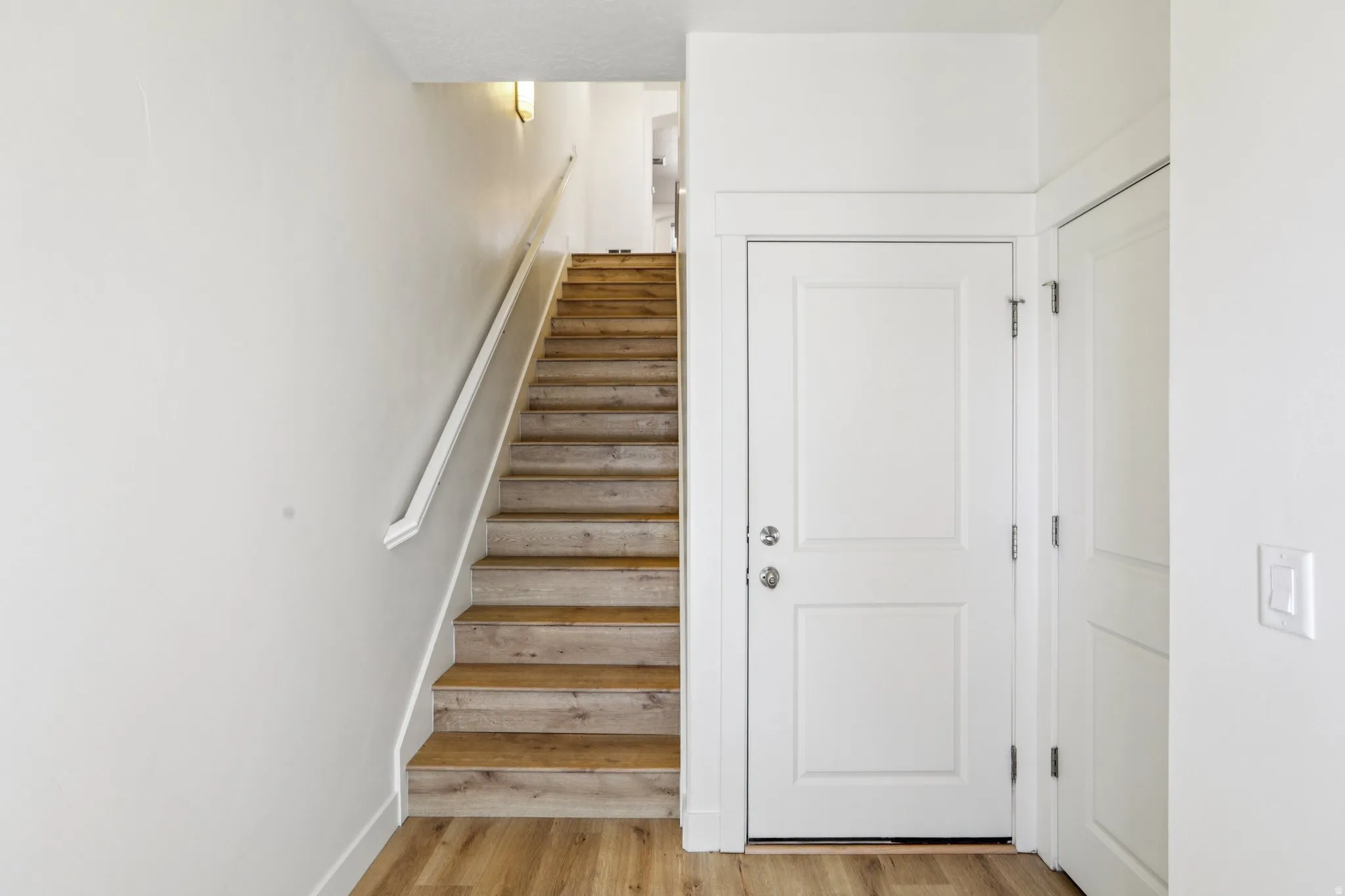 Stairs with wood finished floors and baseboards