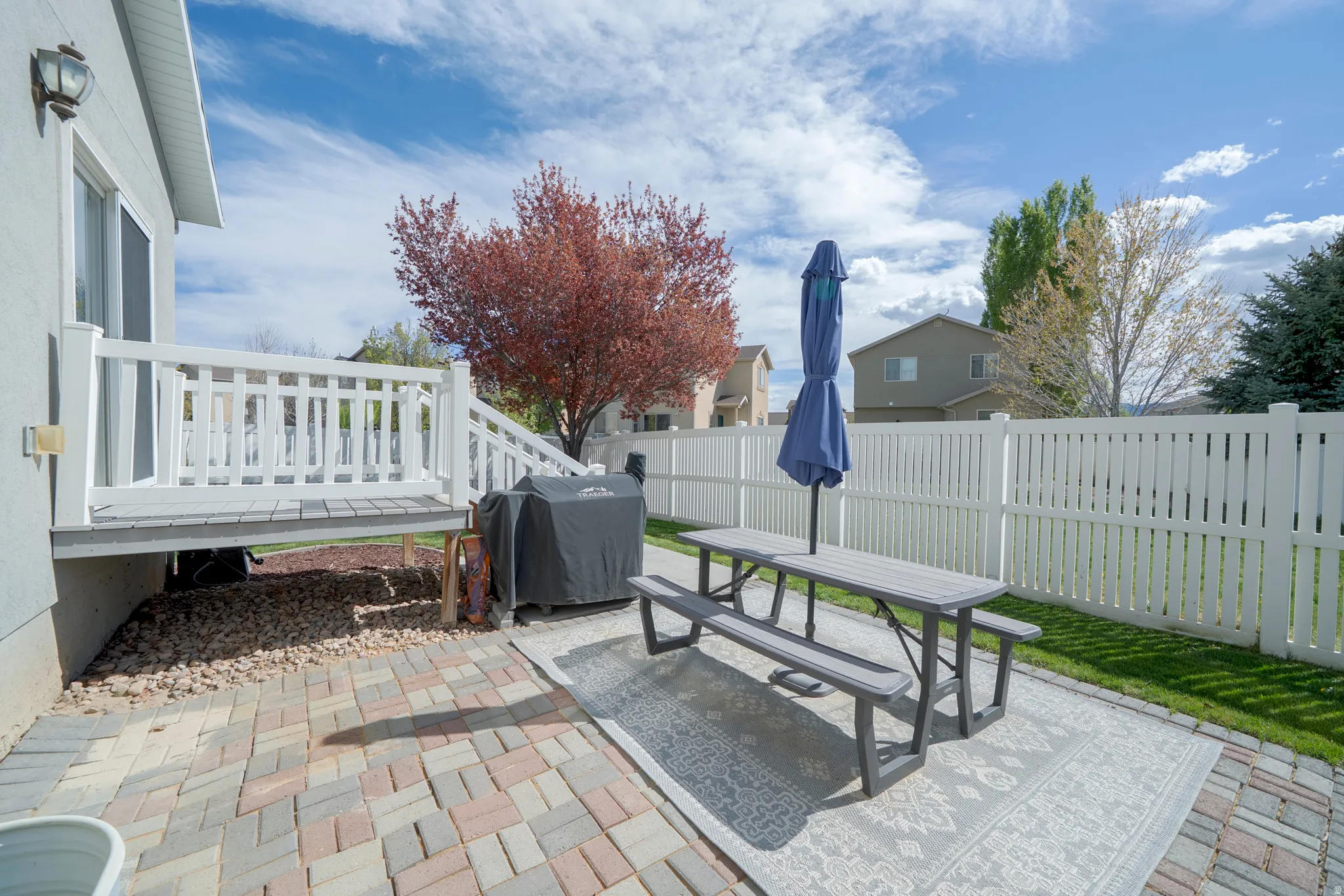 Fenced backyard featuring a patio, outdoor dining area, grilling area, and a wooden deck