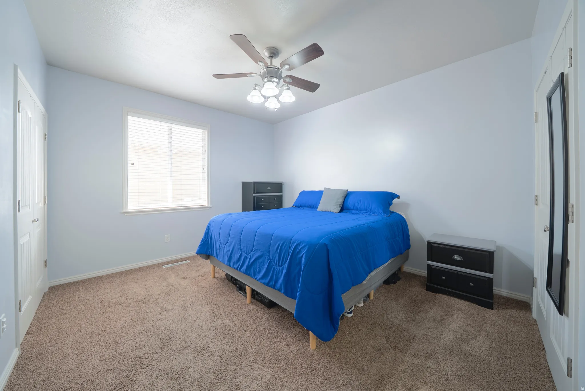Carpeted bedroom featuring a ceiling fan and a closet