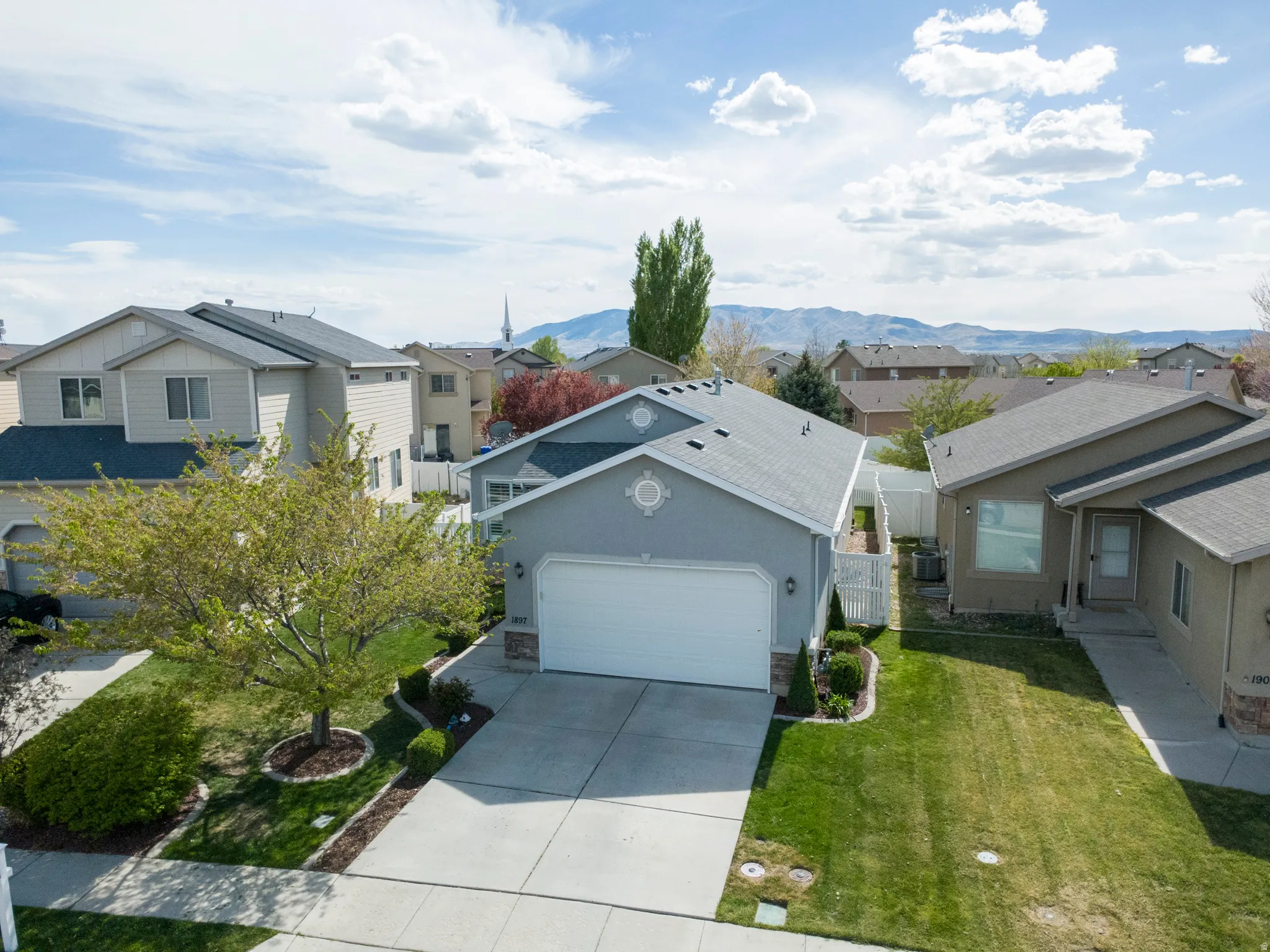 Ranch-style home with a residential view, driveway, a garage, and stucco siding