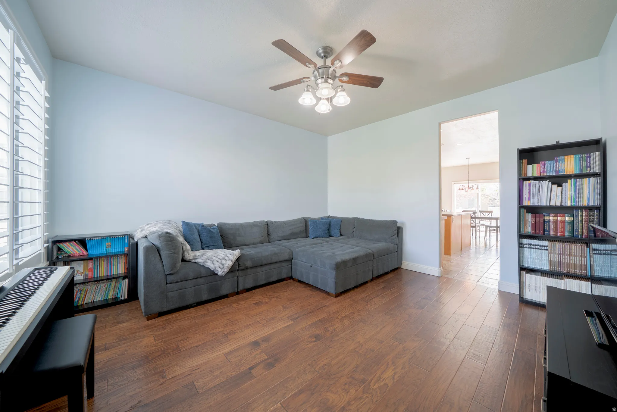 Living room with dark wood-style flooring and a ceiling fan